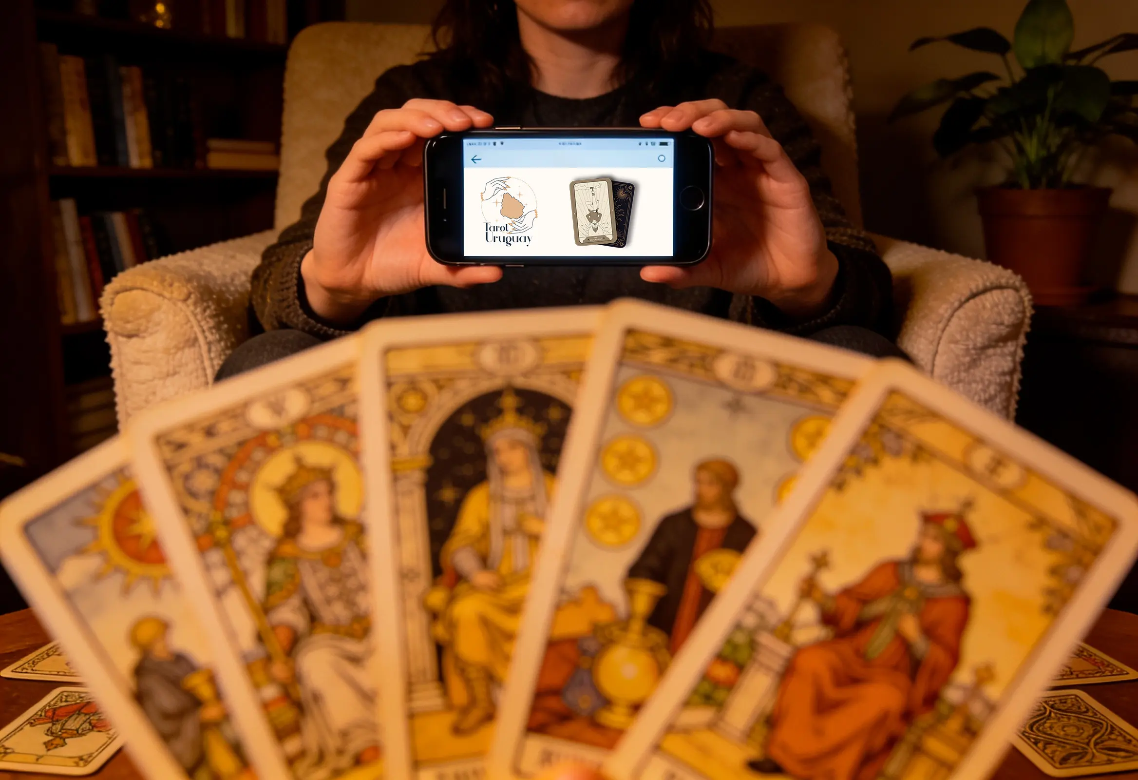 Persona consultando el tarot online en Uruguay de forma confidencial desde su celular, con cartas del tarot Rider Waite desenfocadas en primer plano.